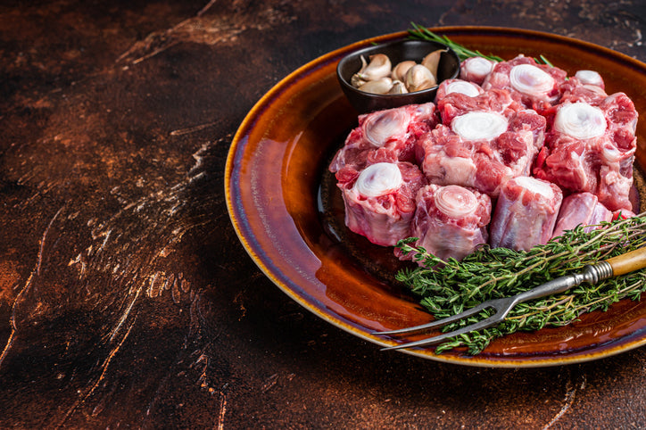 Fresh grass fed beef oxtail cut on rustic plate with herbs