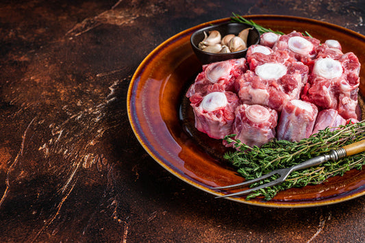 Fresh grass fed beef oxtail cut on rustic plate with herbs