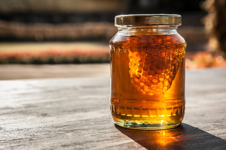 raw honey and honey comb in a jar