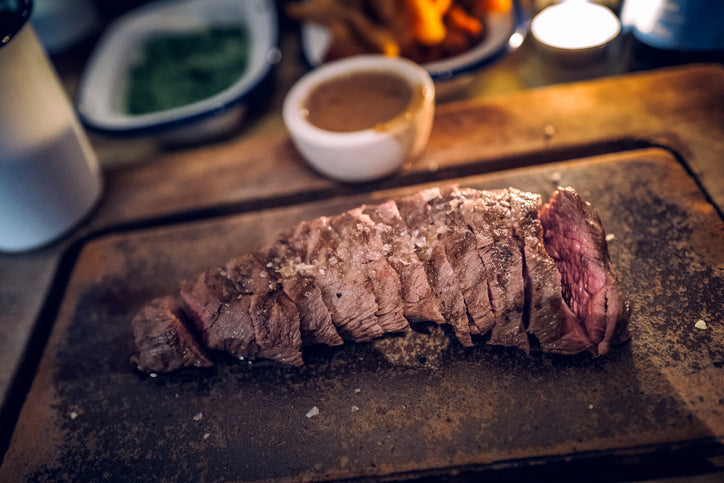 Sliced grass fed flat iron steak on a wooden board