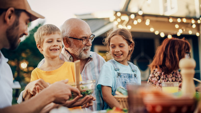 family sitting down to enjoy dinner outside